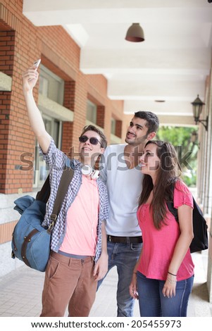 Group of happy friends taking a selfie by smart phone in campus , caucasian