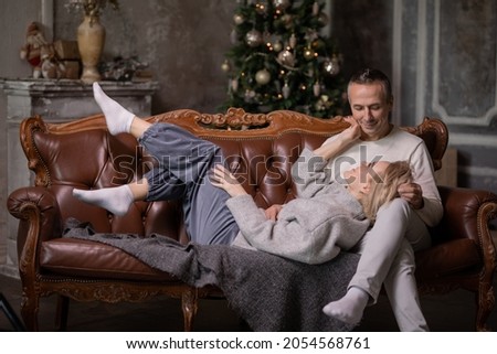 adult woman and man lie on brown couch and hug