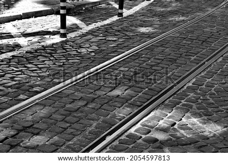 Tram rails on cobblestone street in old town. Black and white image Royalty-Free Stock Photo #2054597813