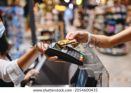Cropped close up woman hand arm shopping at supermaket put credit card to wireless modern bank payment terminal process acquire payments near cashier checkout inside store. People purchasing concept Royalty-Free Stock Photo #2054600435