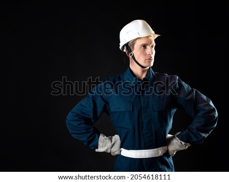 An engineer or architect on a construction site, a man in a robe and a protective helmet on his head, a photo on a black background