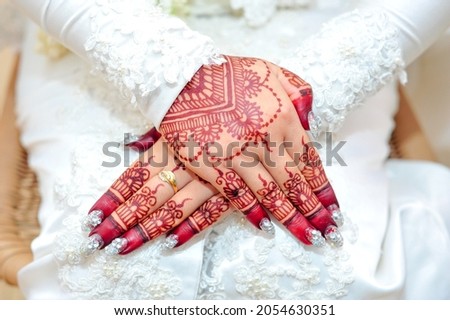 Muslim bride's hands in henna with the ring. closeup hand of the bride painted with red henna. Indonesian wedding. Malay bride henna carved beautiful and unique