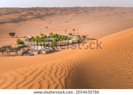 Small camp with trees in the middle of Arabian desert. Oasis in Wahiba Sands, Oman. Hot day in the dunes of Arabian peninsula Royalty-Free Stock Photo #2054630786