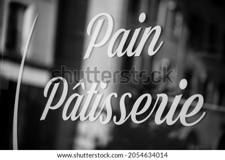 Closeup of traditional sign on french bakery window in french :  pain, patisserie, in english :  bread, pastry