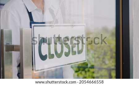 Happy Asian handsome young man staff turning round sign to close on door, Male owner of coffee shop closed the service on window, small business