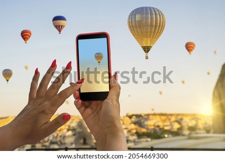 Smartphone in the hands of a woman  taking pictures of a beautiful landscape and balloons in Cappadocia. Sunrise time, dreamy travel concept