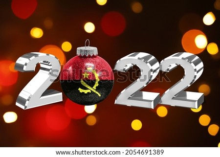 Colorful blurred background and applied the flag of Angola on the New Year's toy. New Year 2022 Celebration