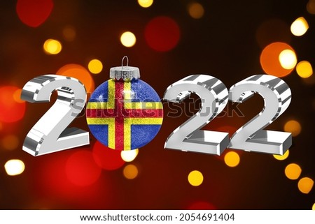 Colorful blurred background and applied the flag of Aland on the New Year's toy. New Year 2022 Celebration