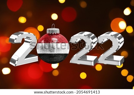 Colorful blurred background and applied the flag of Yemen on the New Year's toy. New Year 2022 Celebration