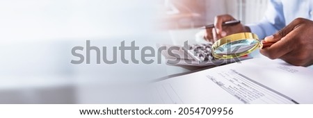 Audit And Fraud Investigation. Auditor Using Magnifying Glass On Document Royalty-Free Stock Photo #2054709956