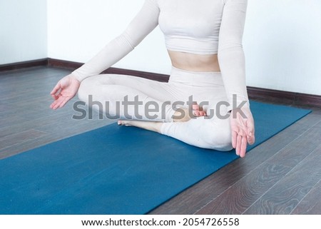 Beautiful girl practices kundalini yoga indoors in daylight. Active lifestyle.