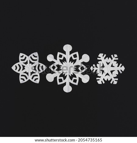 White paper snowflakes on a black background, handmade new year decoration