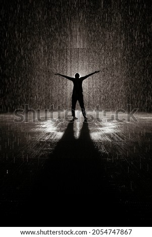 Artistic silhouette of a person hands raised in the rain