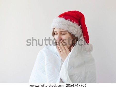 The girl in the Santa hat wrapped herself in a white blanket yawned covered her mouth with her palm and closed her eyes.