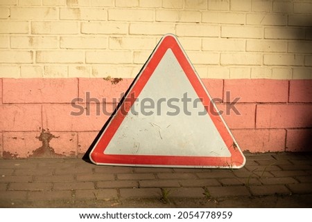 The road sign stands against the wall. The triangle symbolizes traffic. Special symbol for the driver.