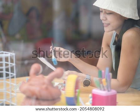 Young asian woman artist painting at home creative take picture through window. Selective focus
