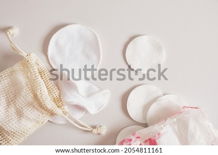 fabric and cotton pads for cleansing the skin from make-up, a mesh bag and a plastic bag for storing them on a beige background Zero waste, reusable, eco, makeup remover and washing concept. Royalty-Free Stock Photo #2054811161