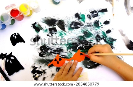 Child making abstract card for the  halloween. Funny crafts from paper. Halloween decor. The concept for Halloween. DIY. 