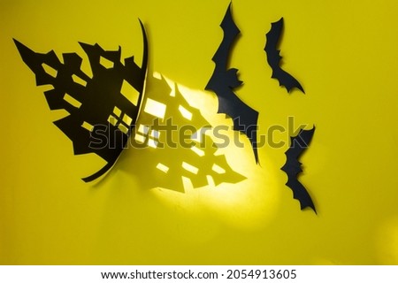  Halloween and decoration concept - bats, gloomy paper house, gloomy black tree branches on a yellow background. house made of paper with a shadow from the house, gloomy shadows of Halloween