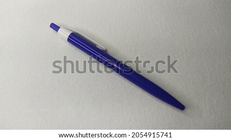 One single closed bright blue plastic pen isolated on blank white canvas paper background with copy space. horizontal close up flat lay macro top view. Education, drawing, study and writer concept.