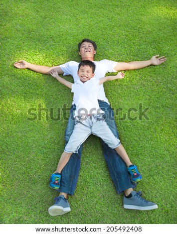 young father and son lying on a meadow together