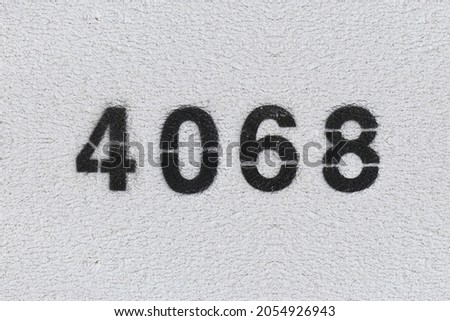 Black Number 4068 on the white wall. Spray paint. Number four thousand sixty eight.