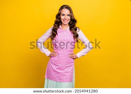 Photo of friendly young brunette housewife lady wear pink shirt apron isolated on yellow color background