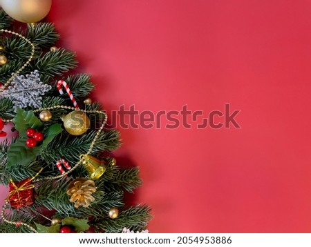 Christmas decorations, pine tree leaves, golden balls, snowflakes, golden berries and red berries on red background