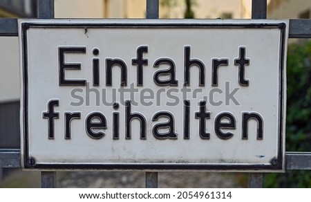 A white sign with the words "Einfahrt freihalten", translation: keep gateway clear, in black letters. 