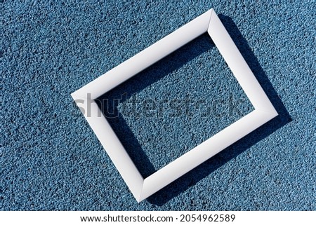 An empty white frame on a blue textured background, with a copy space. Minimal concept.