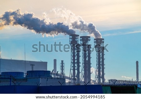 The pipes of the a chemical plant, from which thick white smoke rises into the blue clear sky. Air pollution! Exhaust gases, ozone depletion, greenhouse effect. Industrial landscape of Cherepovets. Royalty-Free Stock Photo #2054994185