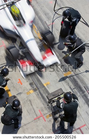 Professional pit crew ready for action as their team's race car arrives in the pit lane during a pitsstop of a car race, concept of ultimate teamwork Royalty-Free Stock Photo #205500526