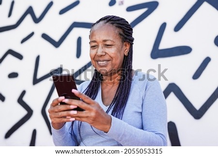 Trendy african american senior woman using mobile phone in the city with black and white background - Elderly black lady enjoy technology Royalty-Free Stock Photo #2055053315