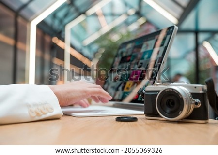 A freelance photographer works remotely, a thin mobile computer with a photo on the screen and a camera in the foreground. Creative work, retouching or creating designs.