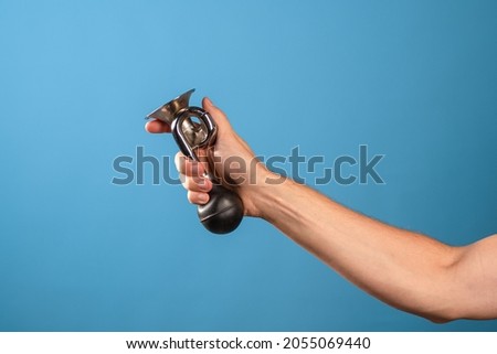 Attention, vintage bicycle horn, loud signal to attract attention. Horn in a man's hand, blue background.