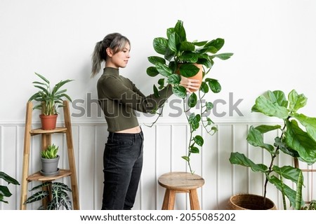 Happy woman carrying a houseplant Royalty-Free Stock Photo #2055085202