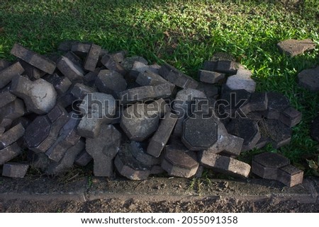 The pile of pavement bricks laying on grass backyard outdoor near the walkway for gardening landscape reconstruction.