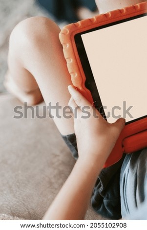 Blond boy learning online with digital tablet