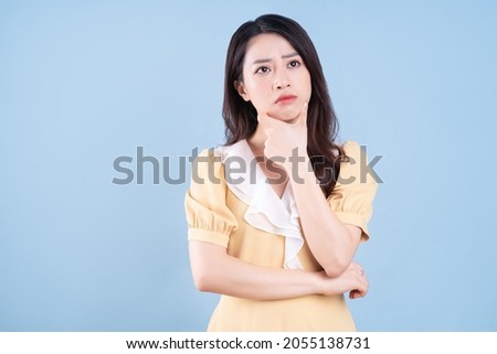 Beautiful Asian young woman wearing yellow dress on blue blackground