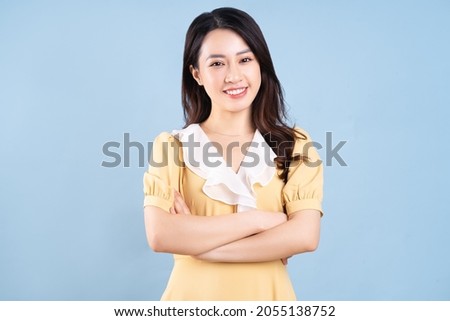 Beautiful Asian young woman wearing yellow dress on blue blackground Royalty-Free Stock Photo #2055138752