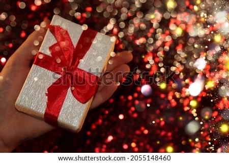  beautiful gift with a red ribbon lies on your hands on a shiny background