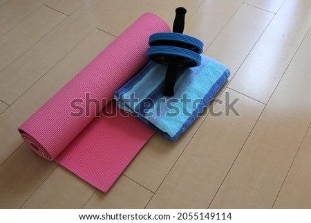 This picture shows there are goods for exercise in home. They are yoga matt , ,roller and towel.