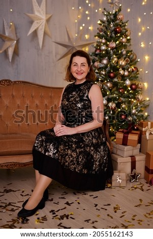Happy woman sitting on sofa near christmas tree