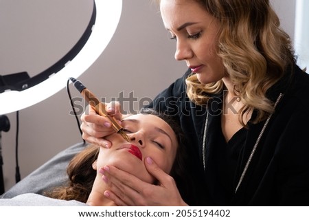 Young woman making lips tatouage in a dressing makeup room. Lips tatouage process .Woman making lips blushing. Make-up artist in beauty studio doing makeup for beautiful girl. Making mua. Royalty-Free Stock Photo #2055194402