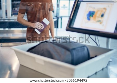 Airport security check. Young man waiting for x-ray control his bag.
 Royalty-Free Stock Photo #2055194492