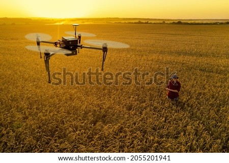 Woman farmer controls drone with a tablet. Smart farming and precision agriculture concept Royalty-Free Stock Photo #2055201941