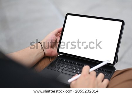 Cropped image of man hand using a white blank screen digital tablet and stylus pen that putting on his lap.
