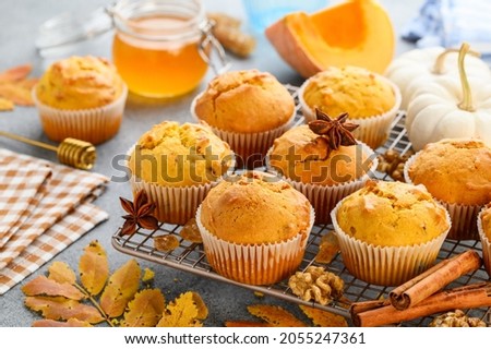 Spicy pumpkin muffins or cupcakes with walnuts on a metal rack. Autumn dessert. Selective focus  Royalty-Free Stock Photo #2055247361