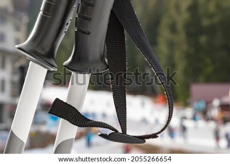 Close-up of pair of ski poles on blurred background of snow covered winter sports area. Alpine skiing, winter family vacation and holiday in mountain resort