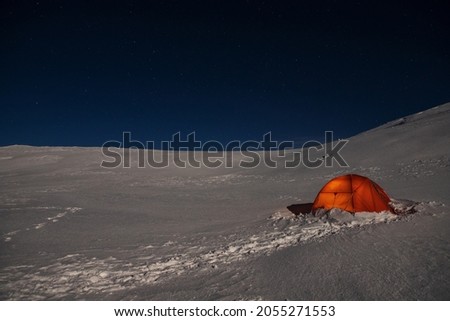 Tent in the winter mountains on a background of starry sky
